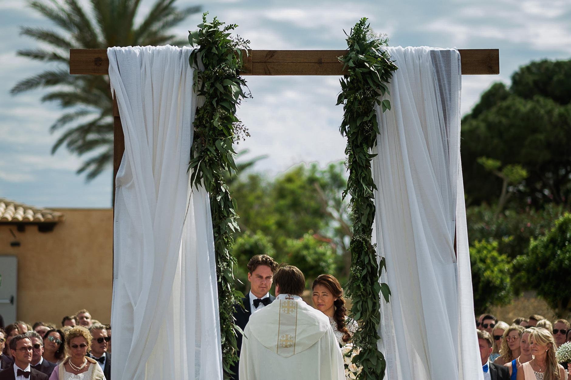 Greenery-covered ceremony arch at a Mallorca field wedding