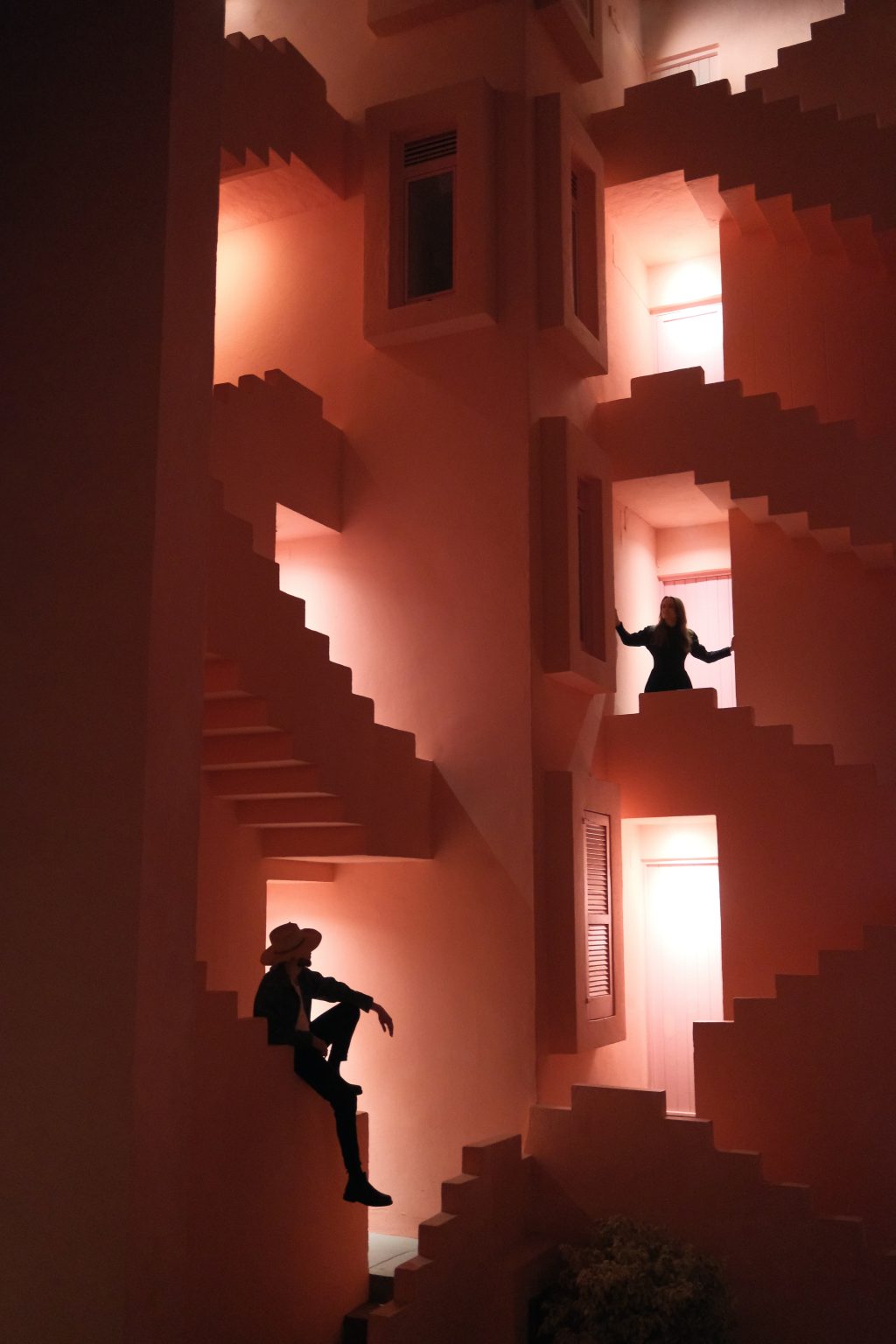 Adriana dancing in a patch of light on a dark pink staircase at Muralla Roja