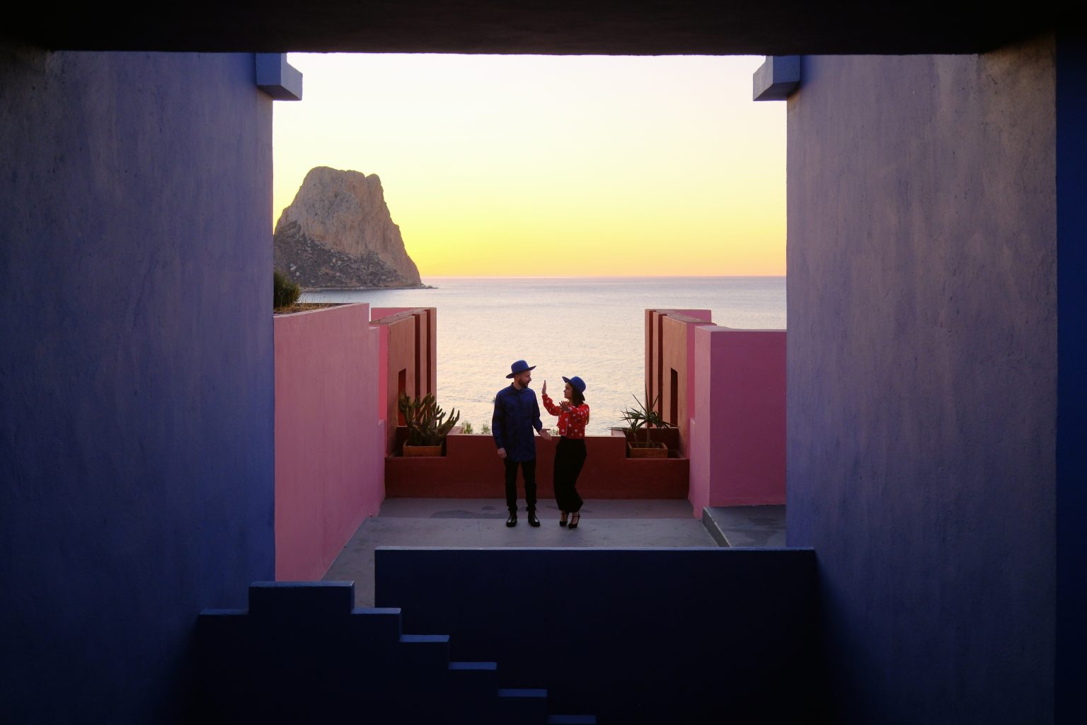 Adriana and Ondrej framed in a pink archway above the Mediterranean at Muralla Roja, Calpe