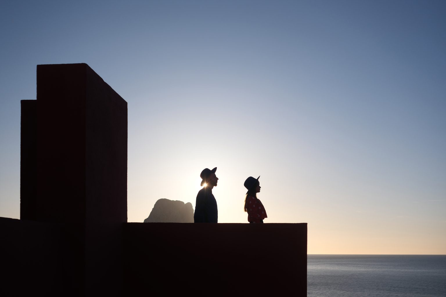 Silhouette of the couple on the rooftop of Muralla Roja as the sun sets over Calpe