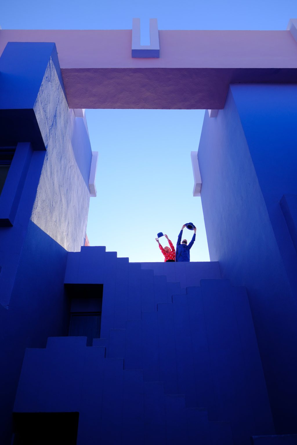 Adriana and Ondrej leaning over a blue parapet against the sky at Muralla Roja