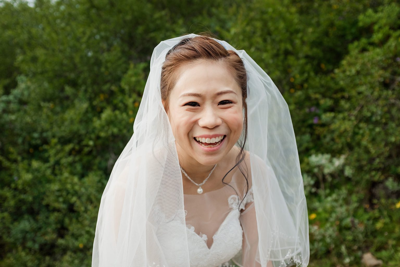 The bride laughing through her veil at Brúarfoss