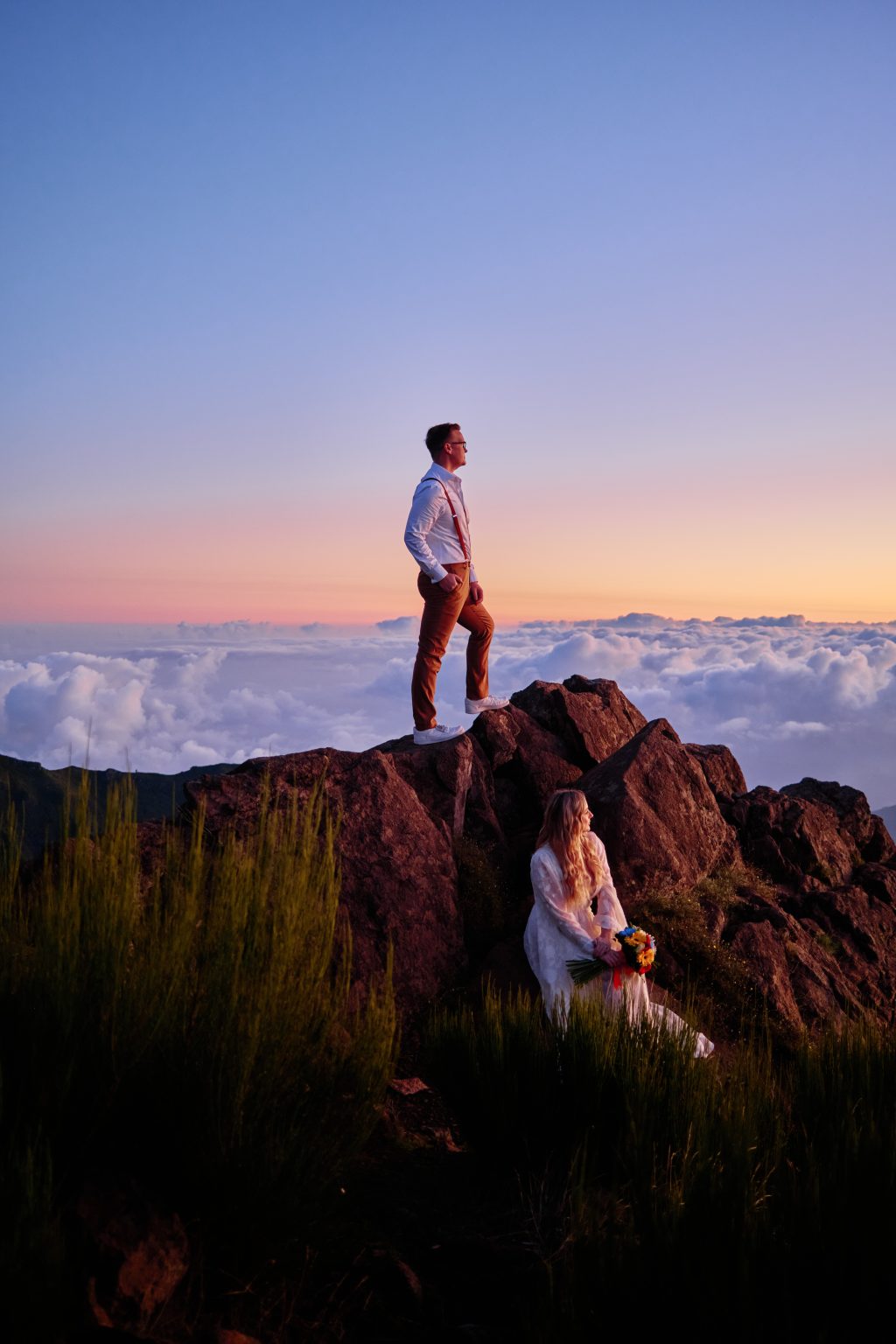 Groom standing on a peak above the clouds at sunrise, Madeira