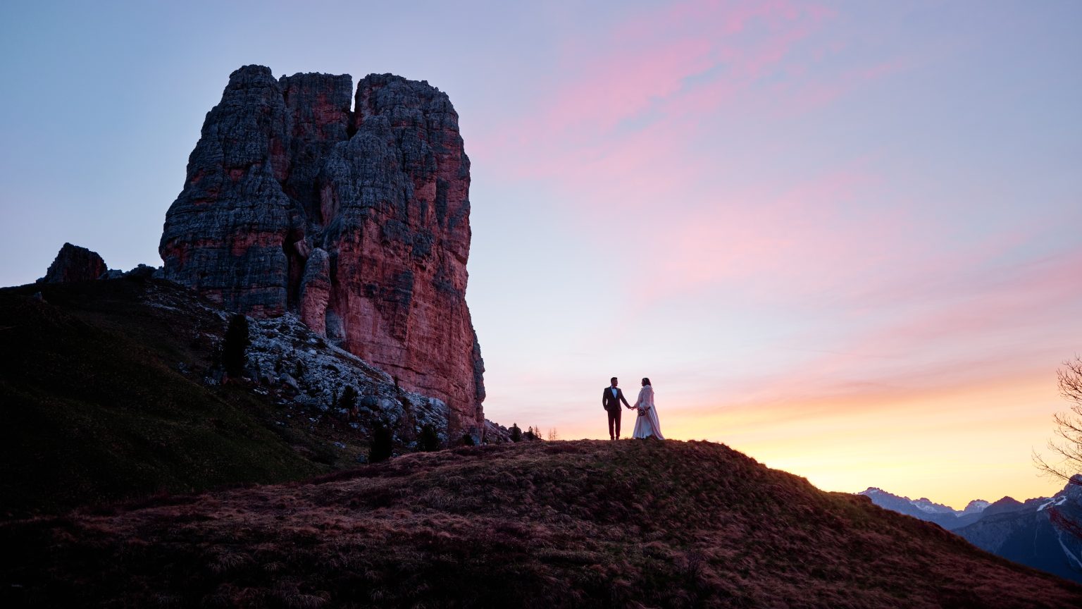 Elisa and Hector silhouetted on a ridge at Cinque Torri during a Dolomites sunrise engagement session