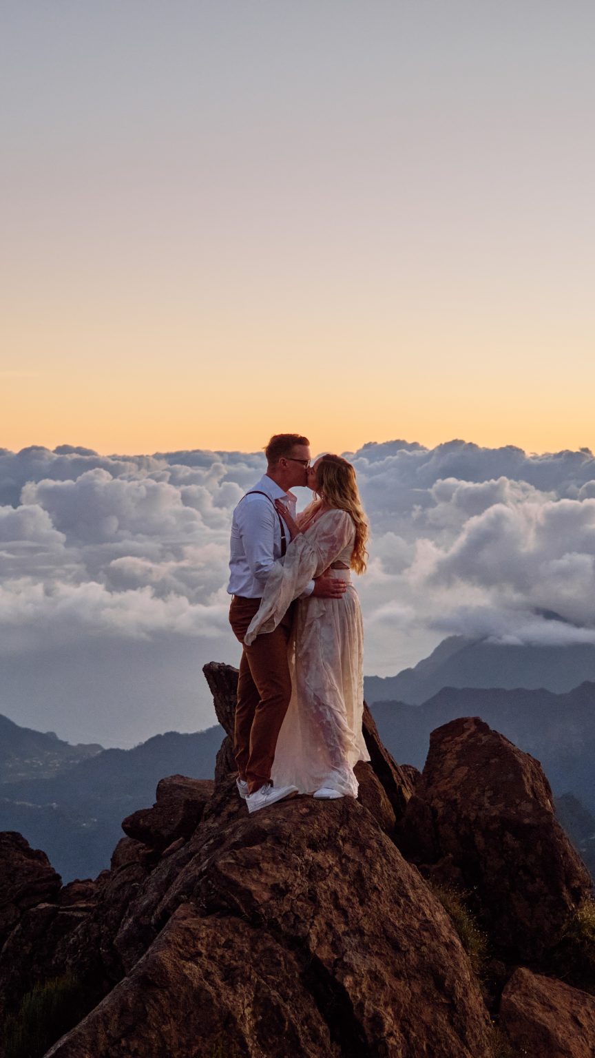 Couple embracing above a sea of clouds at sunrise, Madeira
