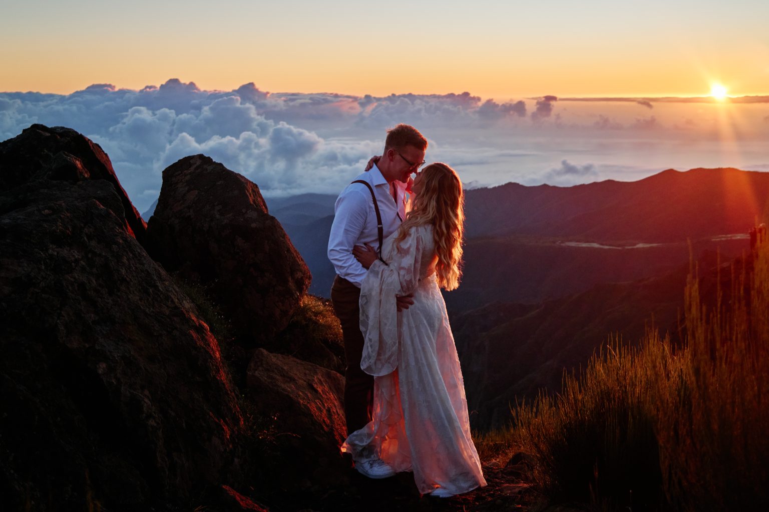 Couple standing above the clouds at sunrise on Pico do Arieiro, Madeira