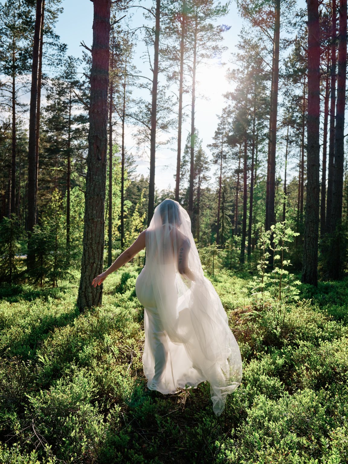 Sara walking through the mossy forest in her veil at a Sweden cabin elopement
