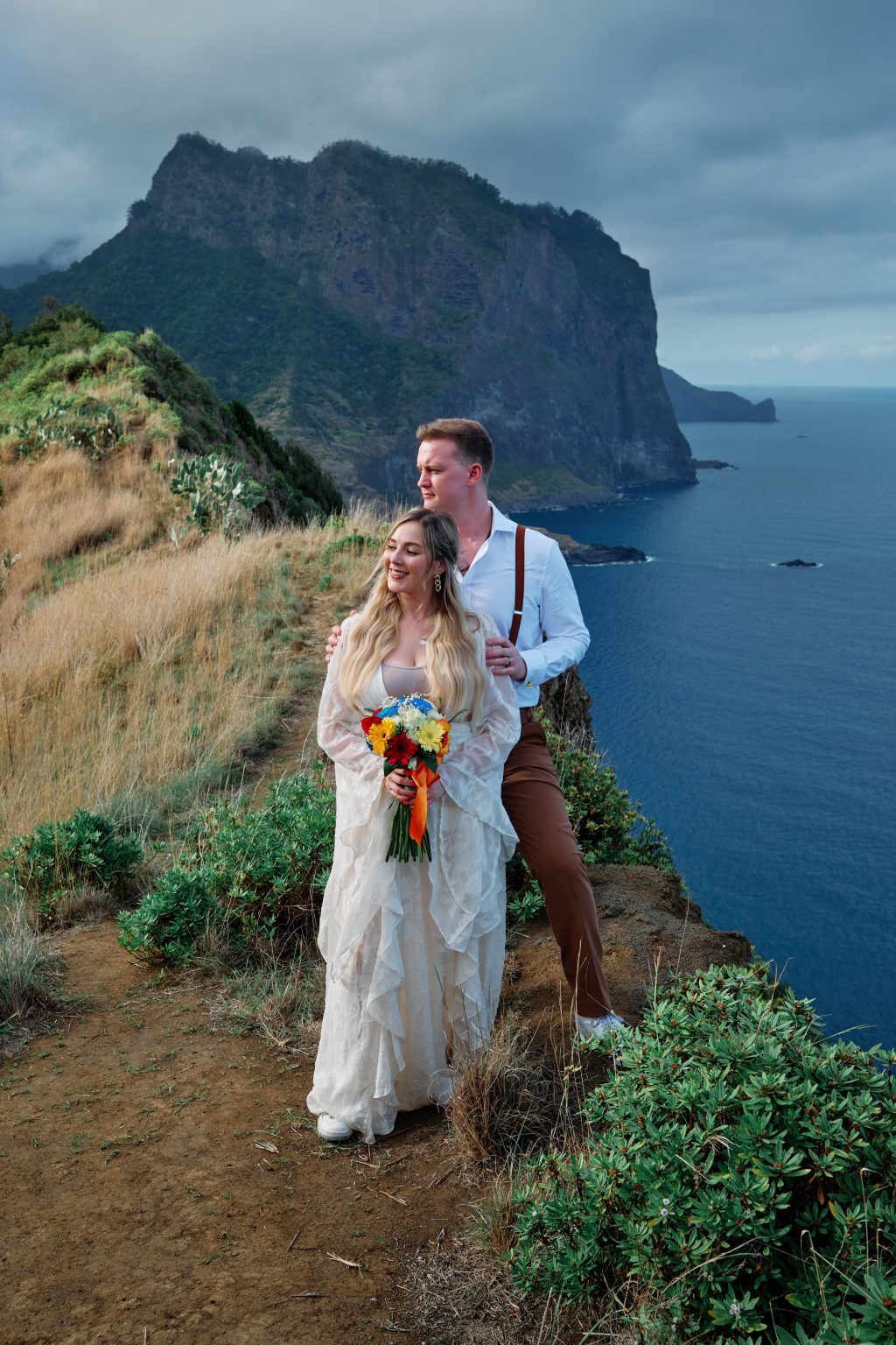 Couple embracing on a green cliff above the sea, Ponta de Sao Lourenco, Madeira