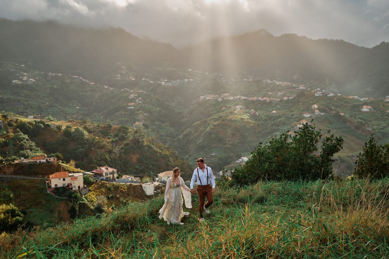 Couple small in a green valley as light breaks through, Queimadas, Madeira