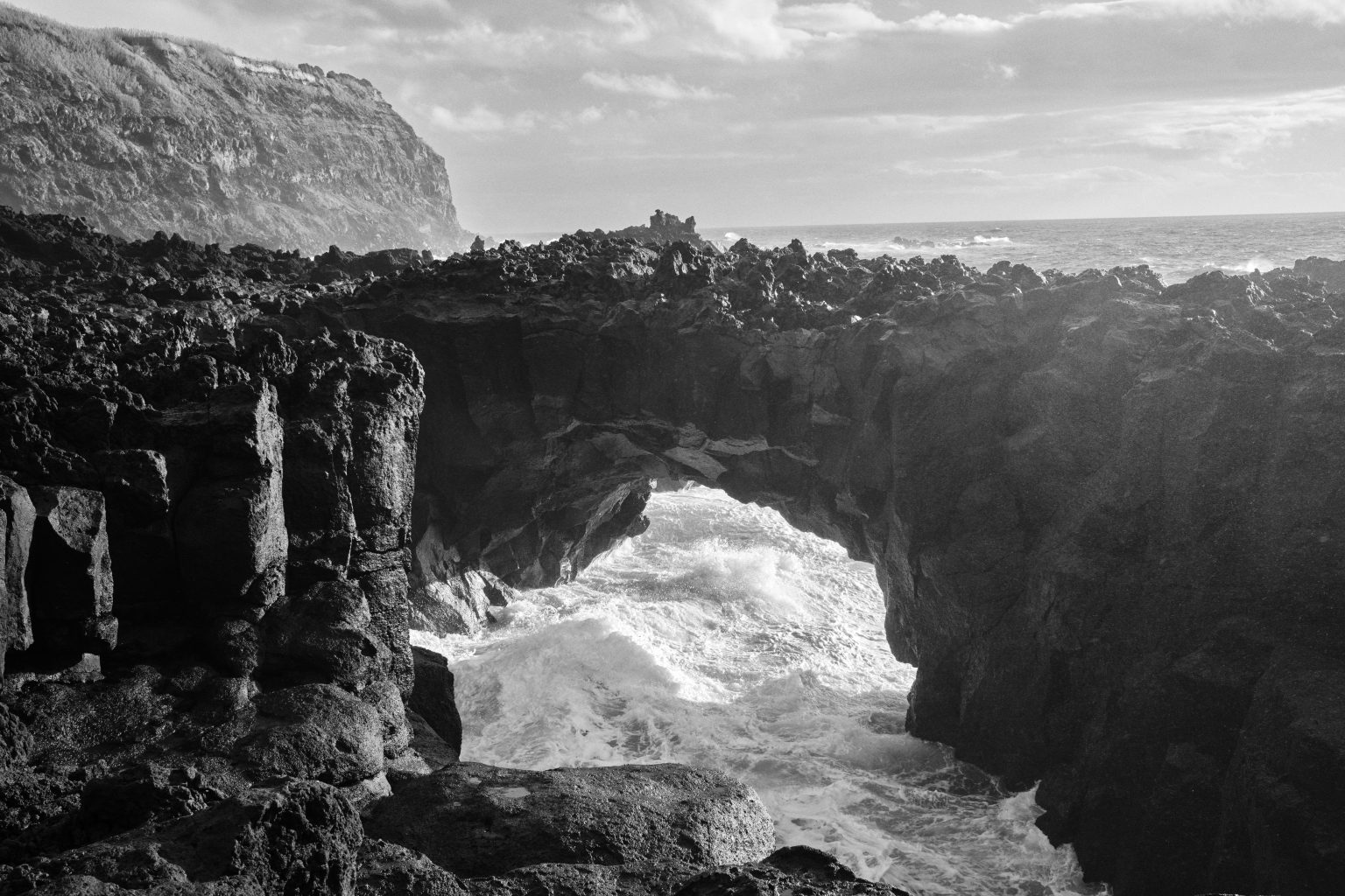 Black lava arches over the surf on São Miguel