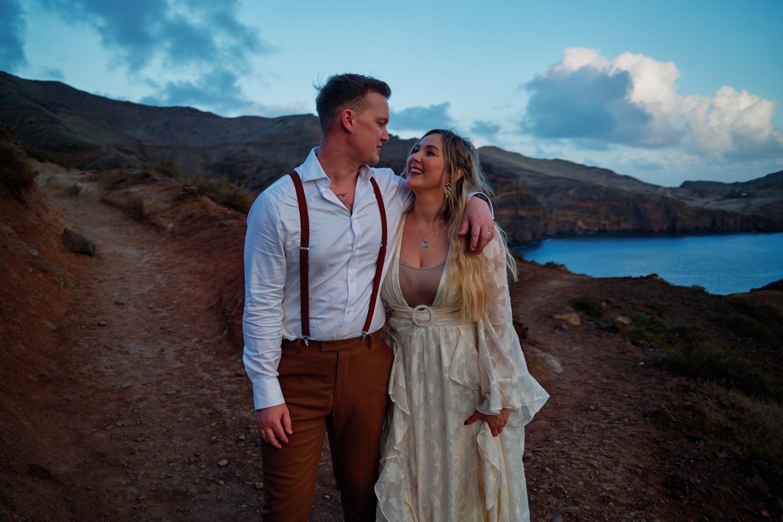Couple on a green cliff with volcanic islets behind, Ponta de Sao Lourenco, Madeira