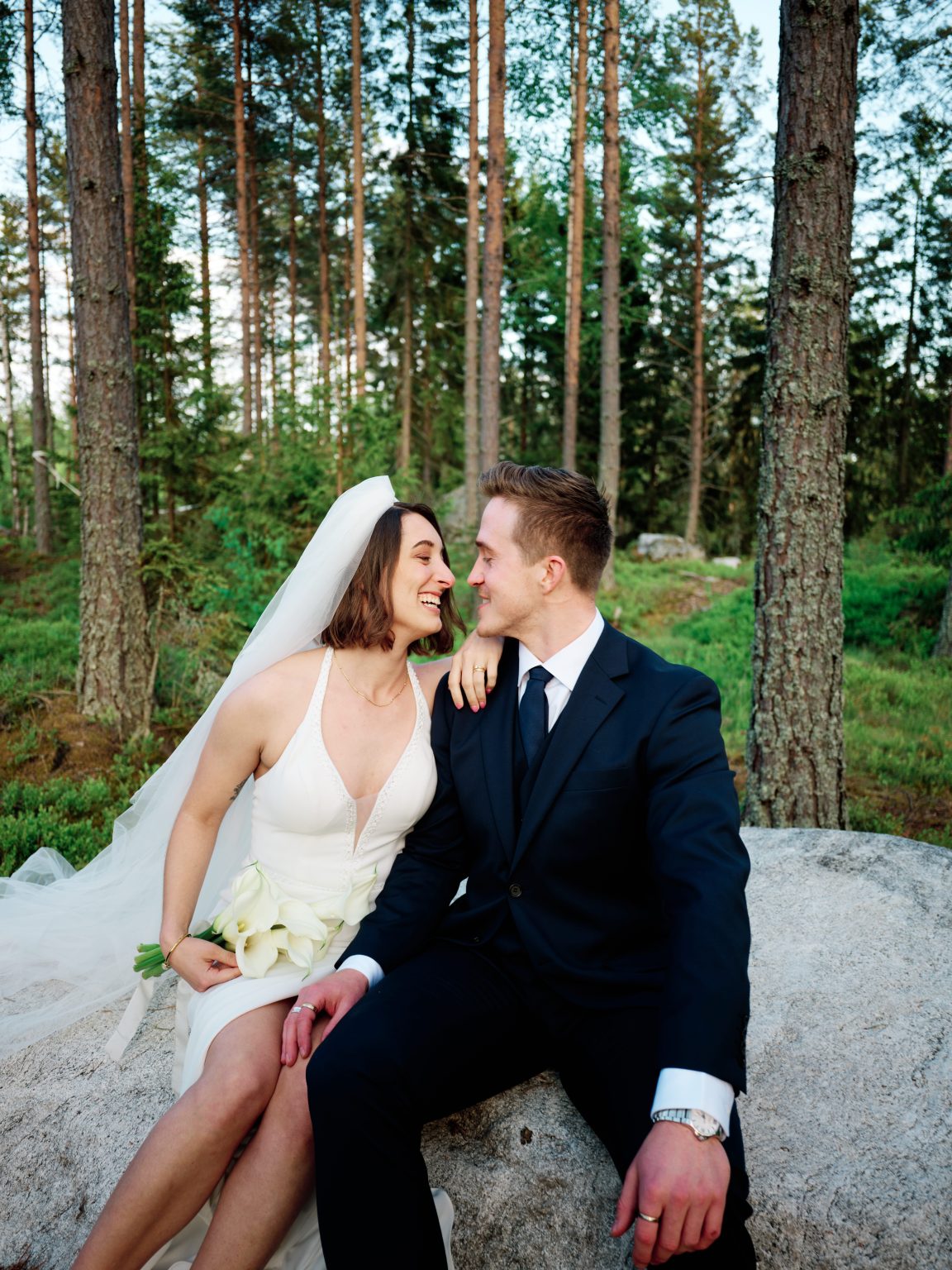 Sara and Martin sitting on a mossy boulder, foreheads together