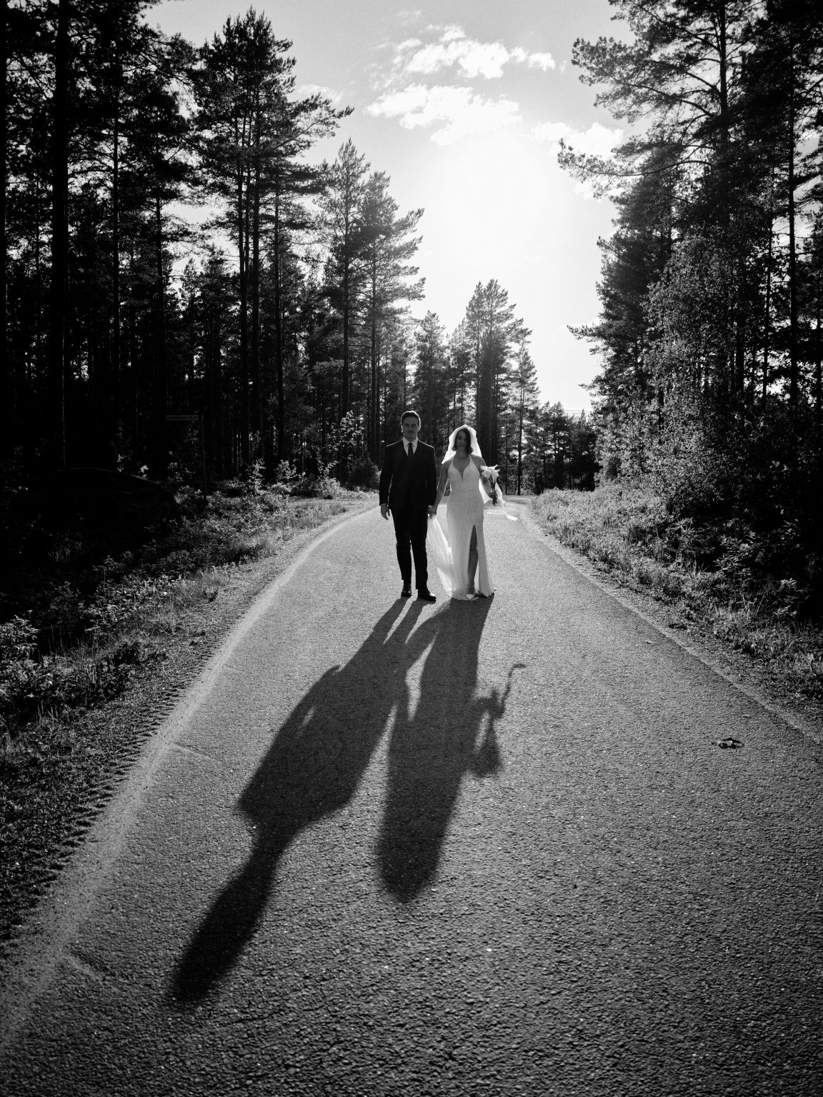 Sara and Martin walking the gravel road in black and white, long shadows