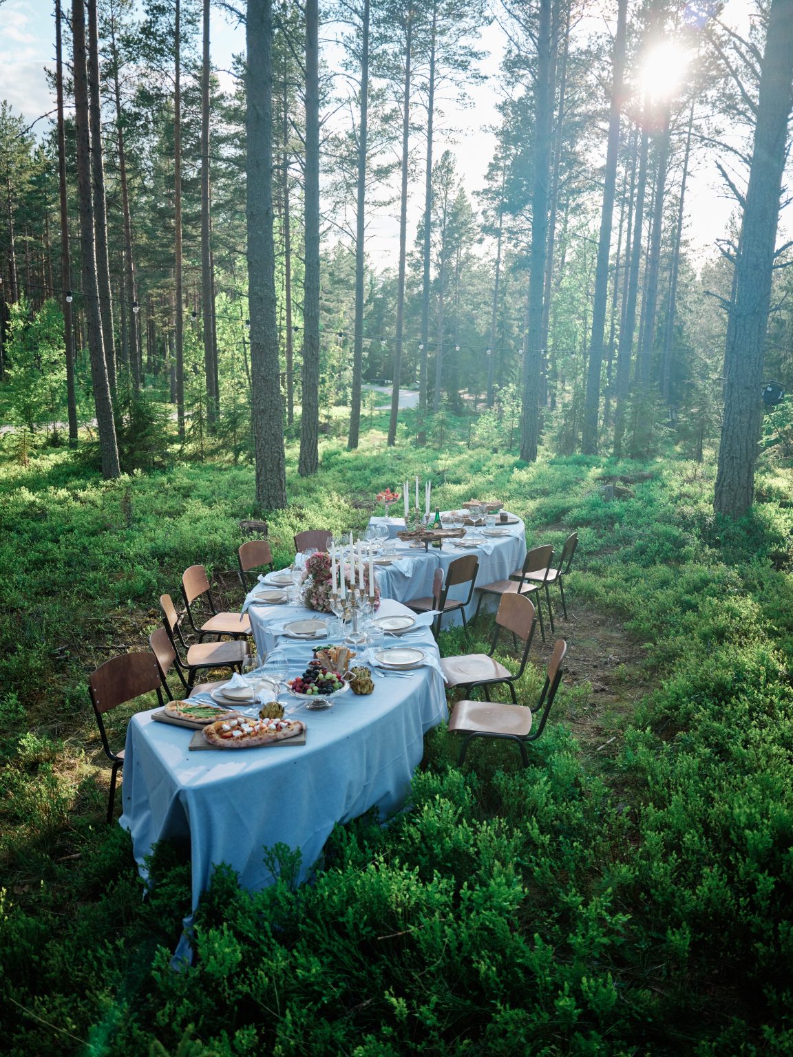 A long wedding table winding through the forest at Hop Farm Beach