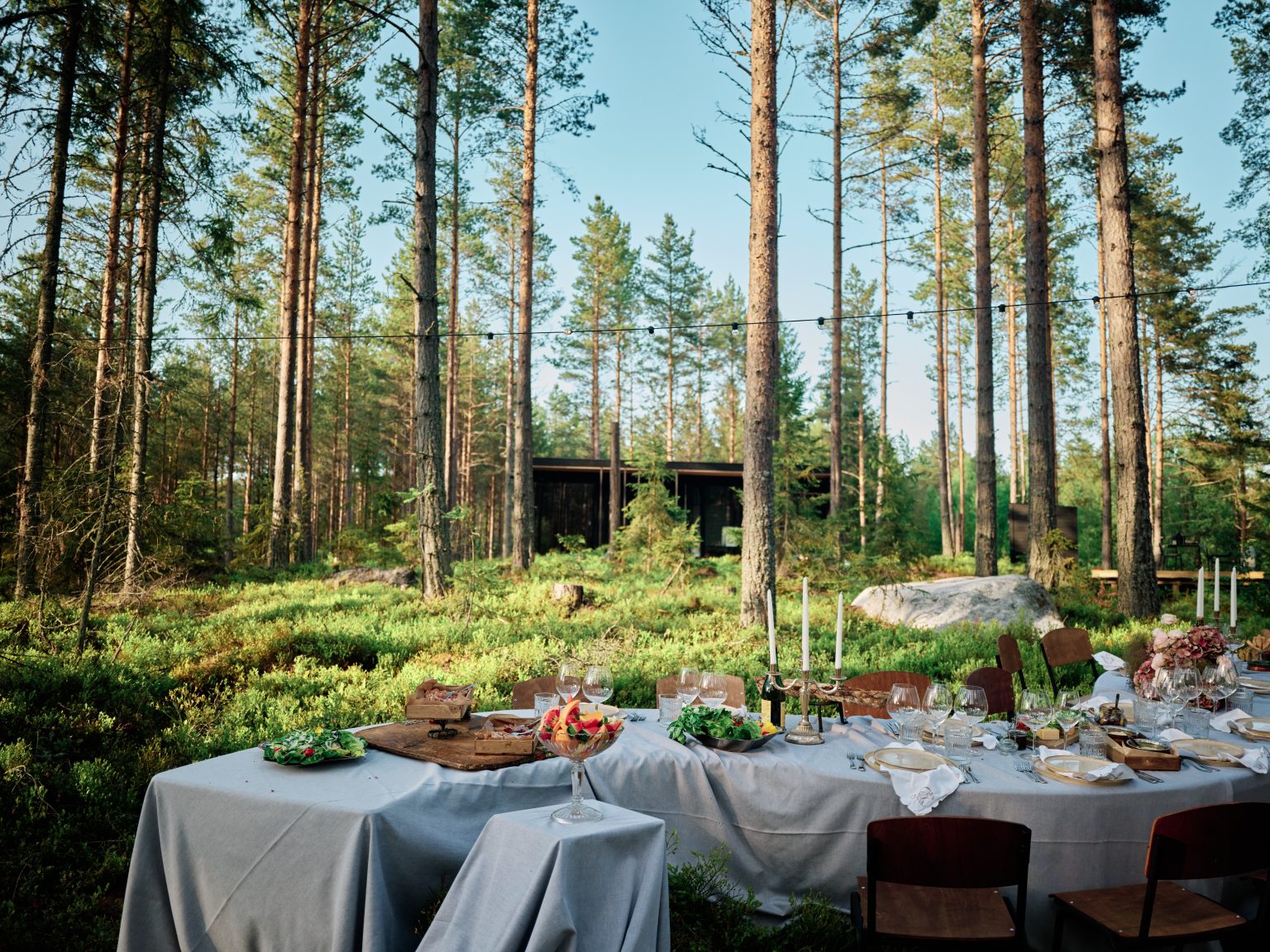 The wedding table in the forest with the black cabin behind, Hop Farm Beach Sweden