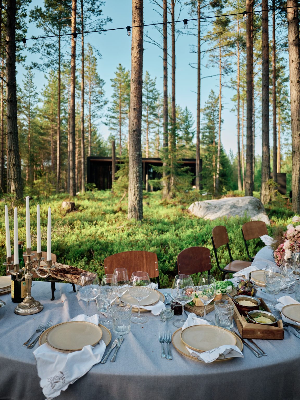 Candles on the forest table with the cabin in the trees