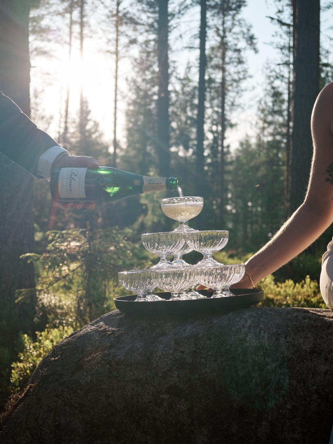 A champagne tower poured on a boulder in the forest