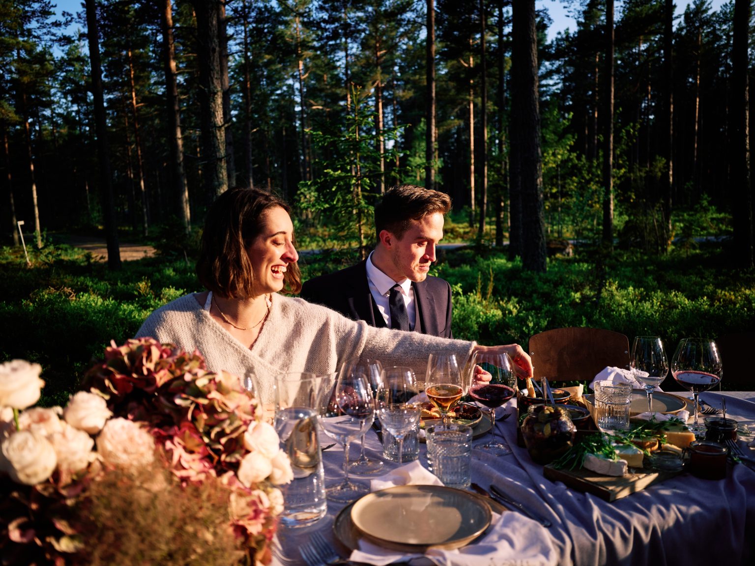 Sara and Martin laughing at the forest dinner table