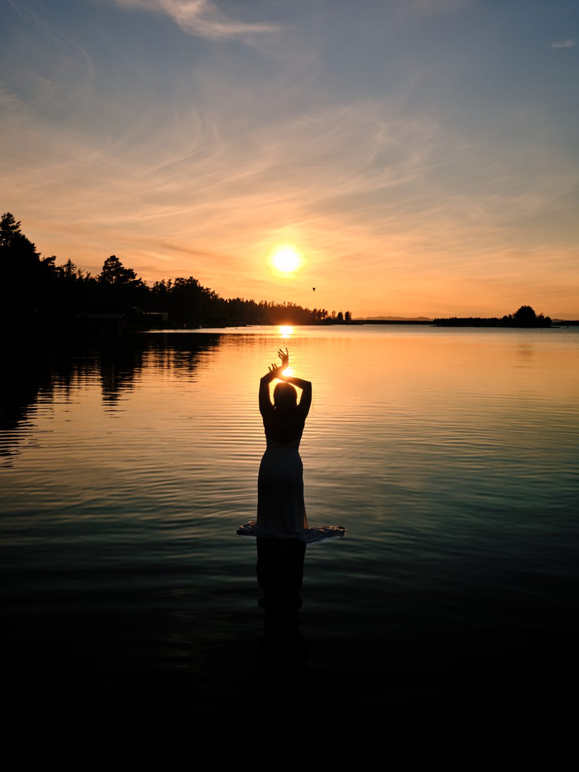 Sara holding the sun in the Baltic at a Sweden cabin elopement