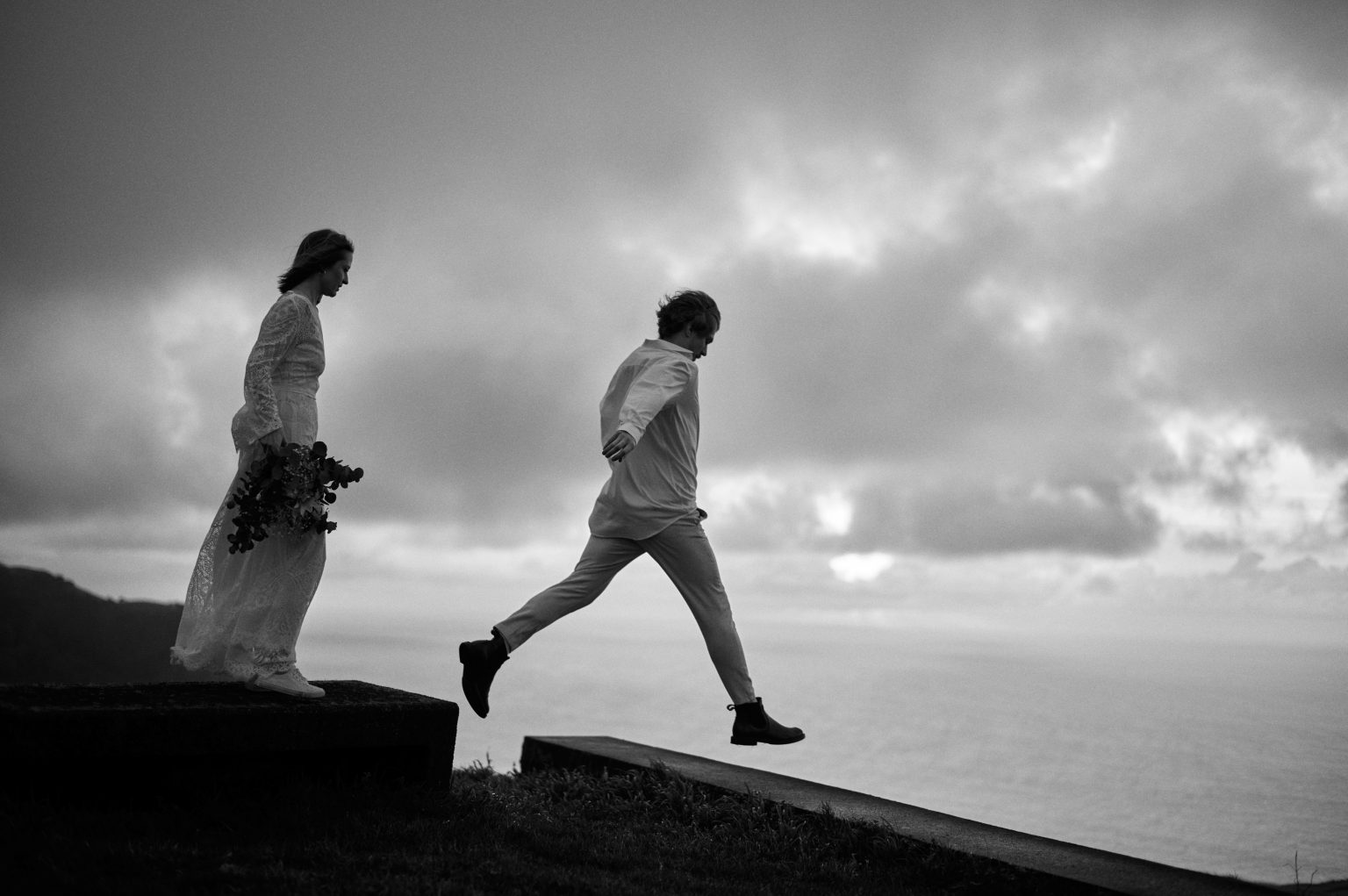 Kasia and Kostek walking a stone wall above the Atlantic on São Miguel, Azores