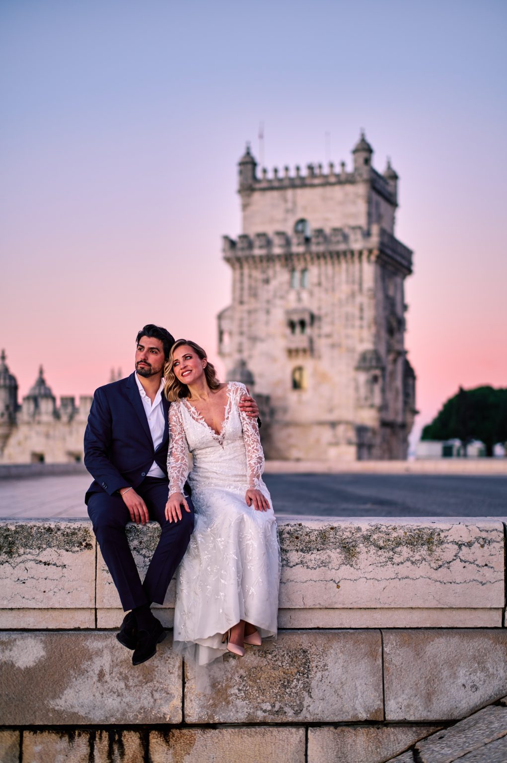 Ana and David sitting beneath the Torre de Belém at sunrise