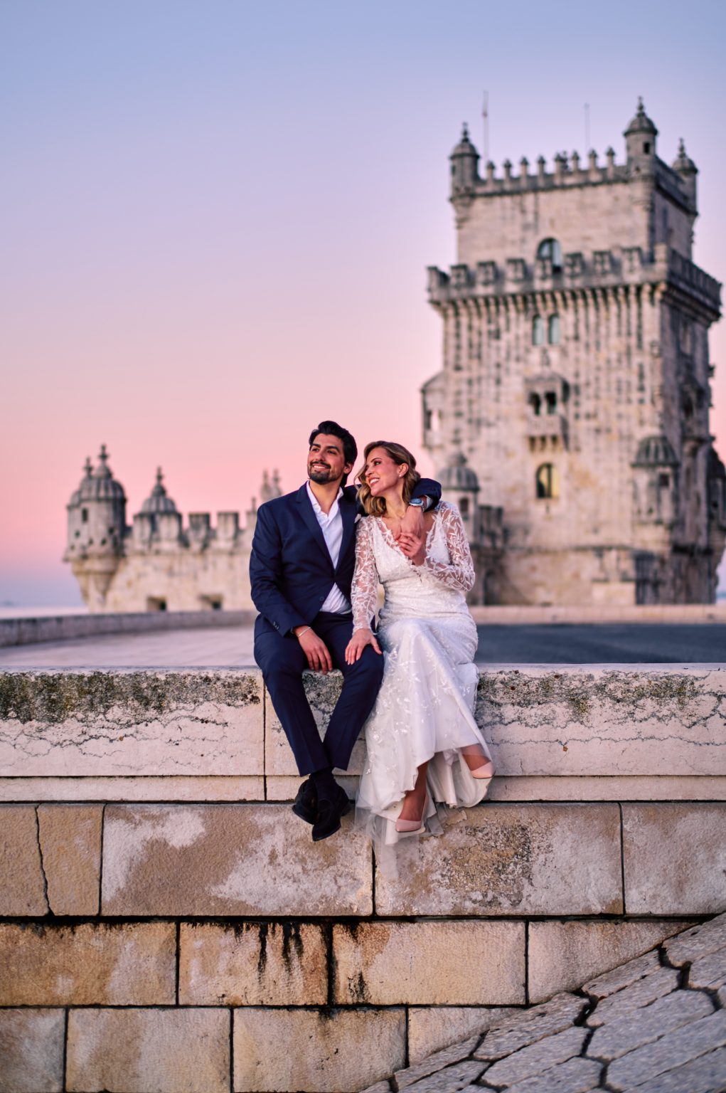 Ana and David on the seawall at the Torre de Belém in the pink sunrise light