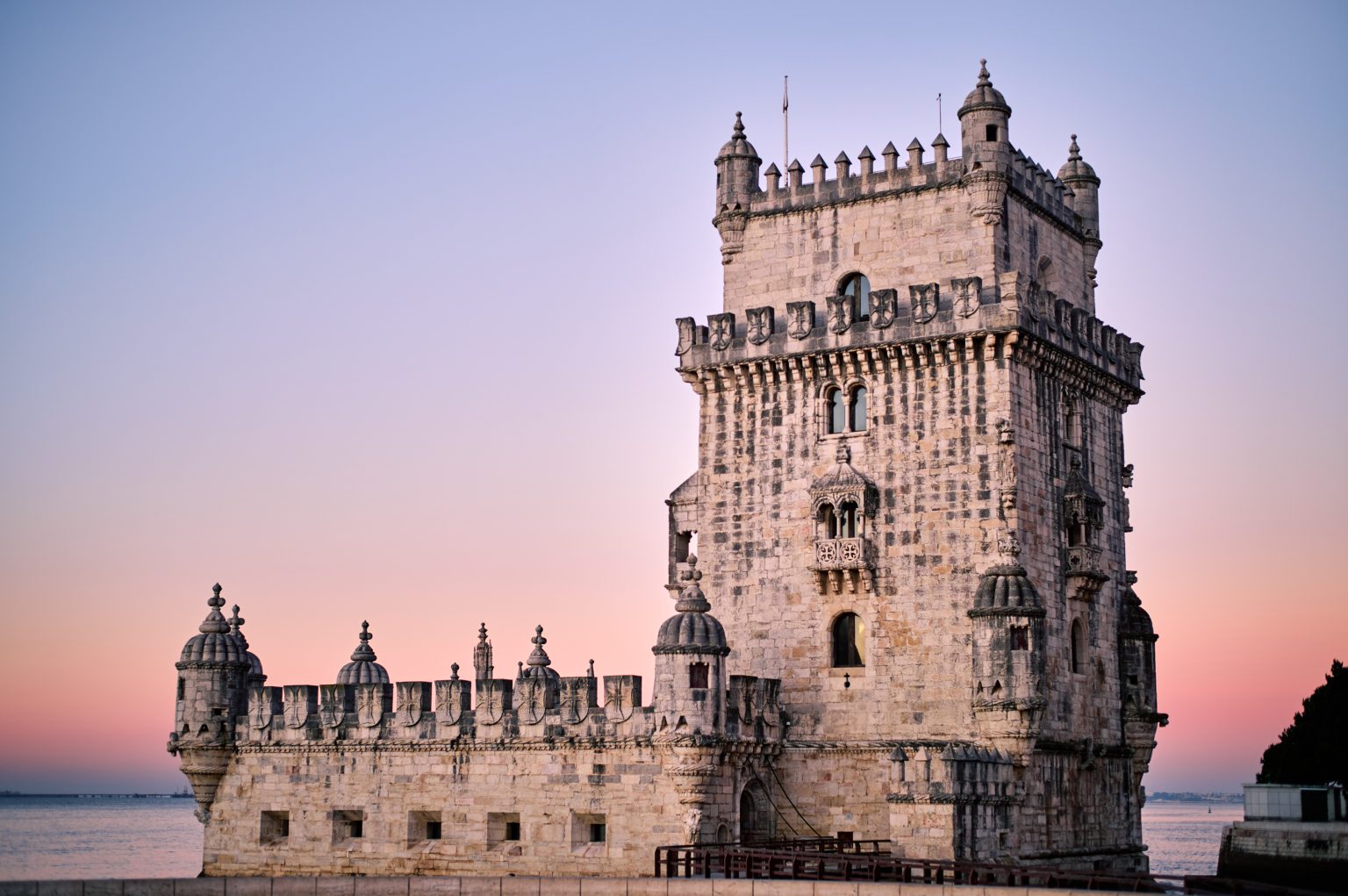 The Torre de Belém against a pink sunrise sky in Lisbon