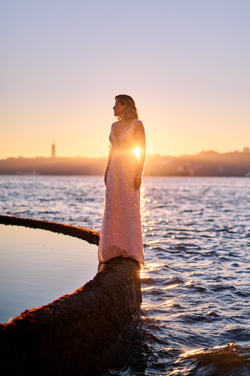 Golden sunrise light through Ana’s dress at the edge of the Tejo