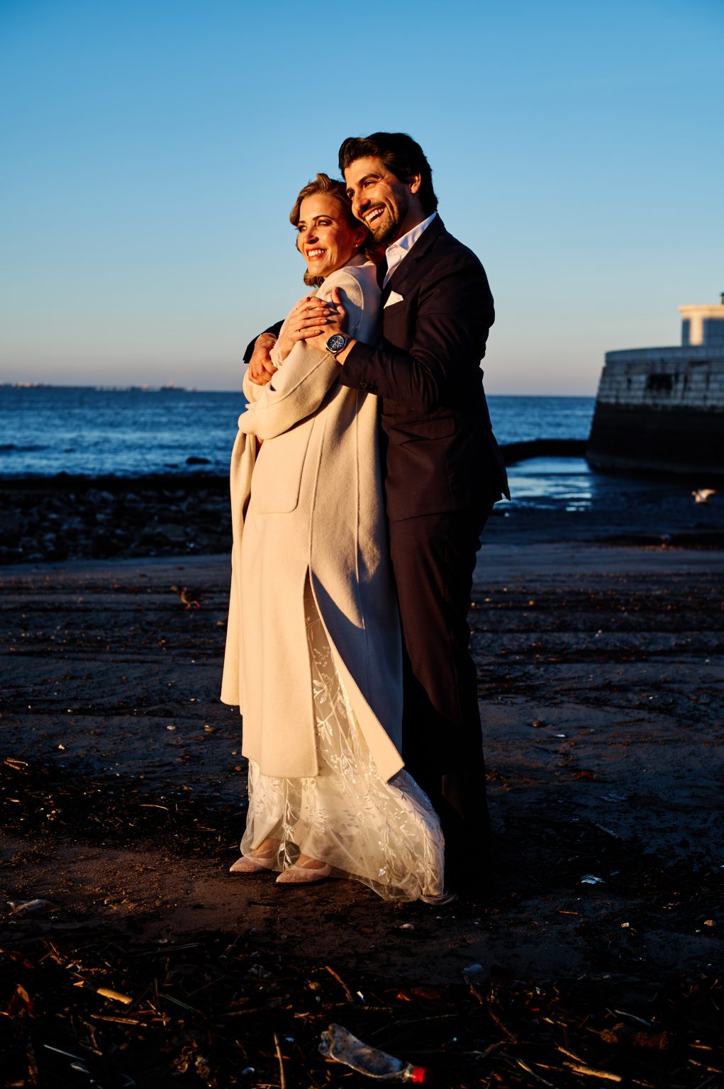 Detail of Ana’s coat and dress on the sand beside the Tejo