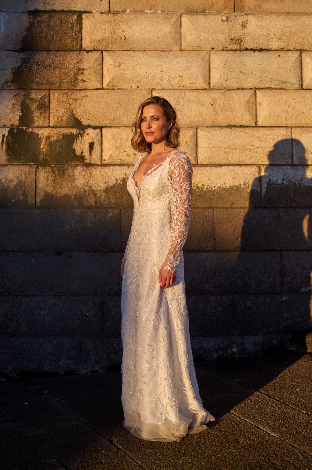Ana in a lace Buch Couture dress against the stone wall in Belém