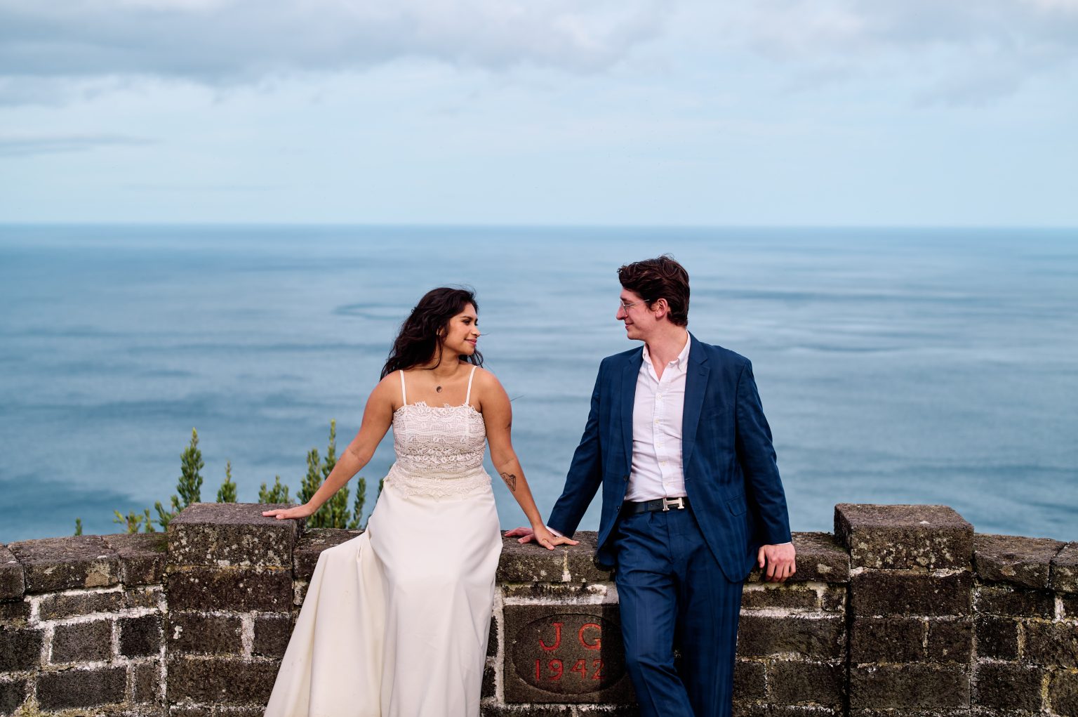 Couple on a stone wall above the water, São Miguel, Azores