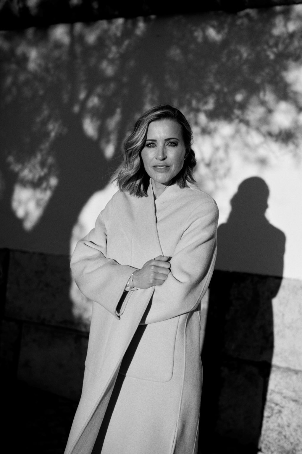 Black and white portrait of Ana with tree shadows on the wall behind her