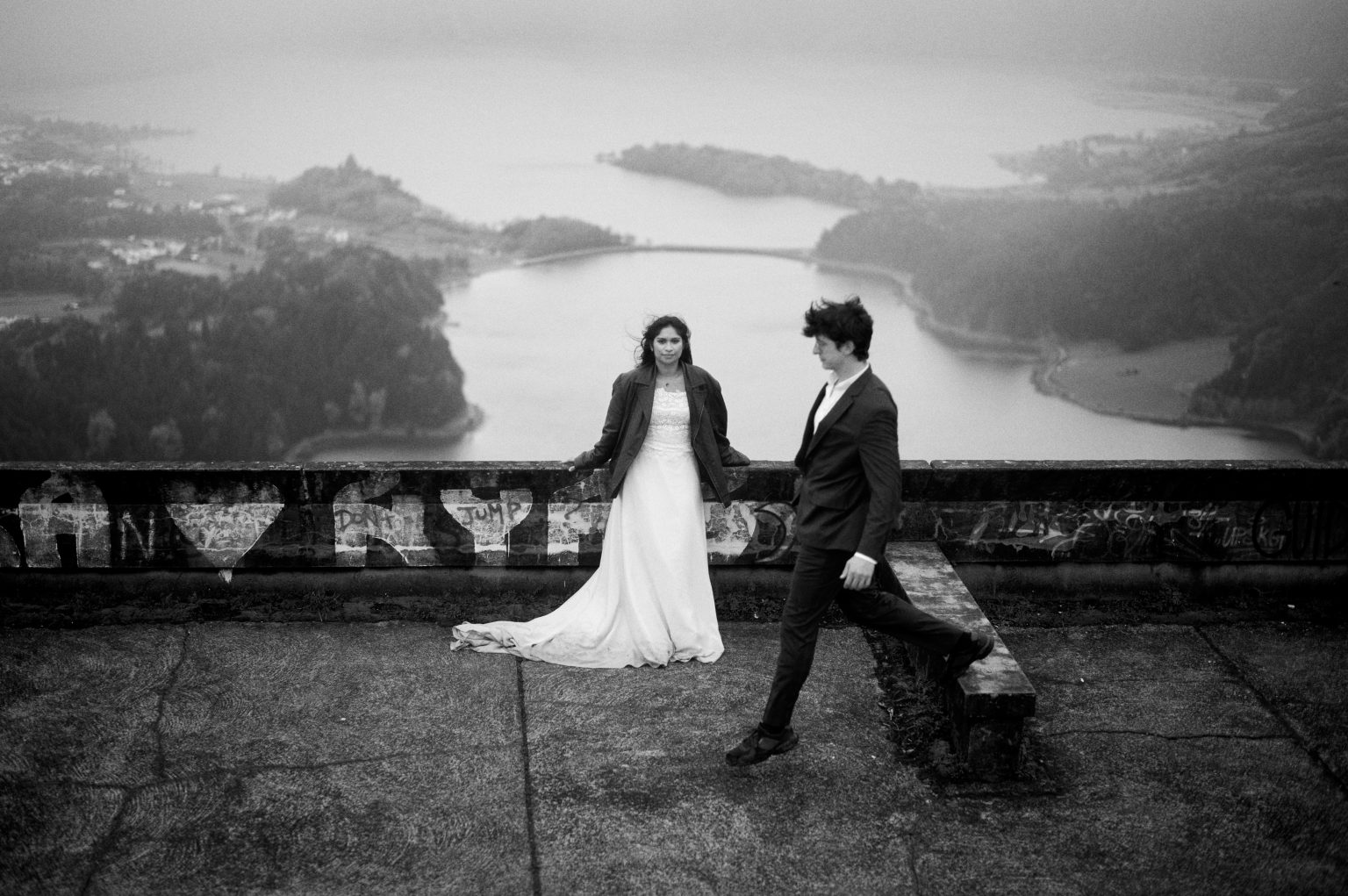 Couple at a crater lake viewpoint under a heavy sky, black and white, São Miguel, Azores