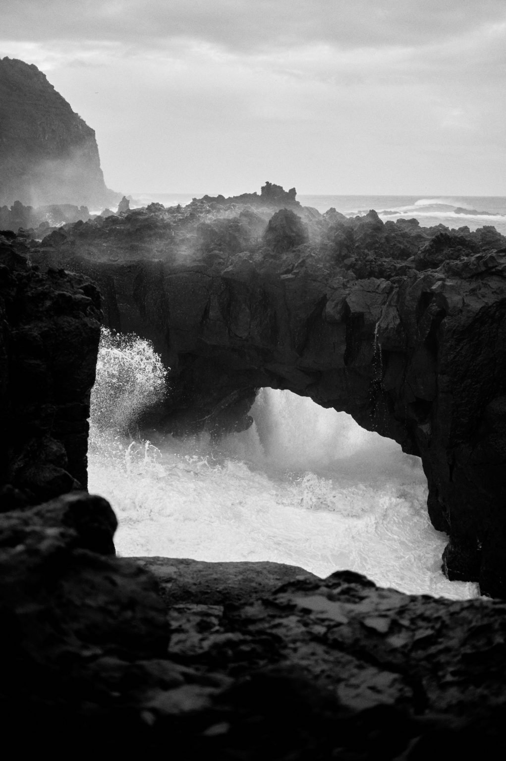 Sea arch in the lava coast with breaking surf, black and white, São Miguel, Azores