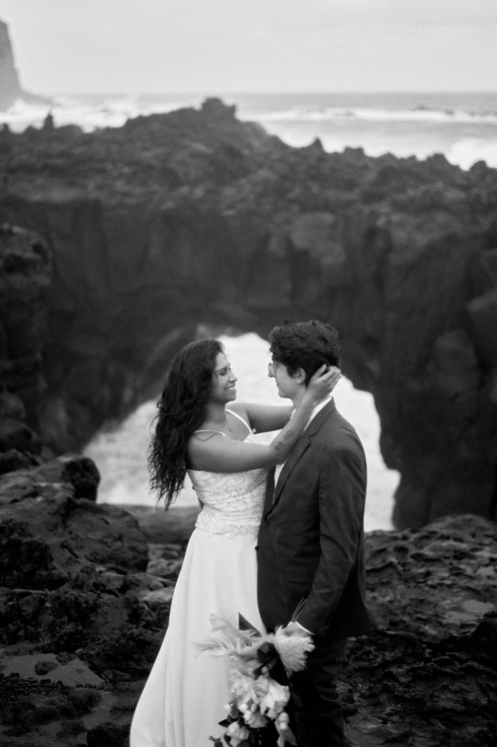 Couple embracing in the sea spray at Ponta da Ferraria, black and white, São Miguel