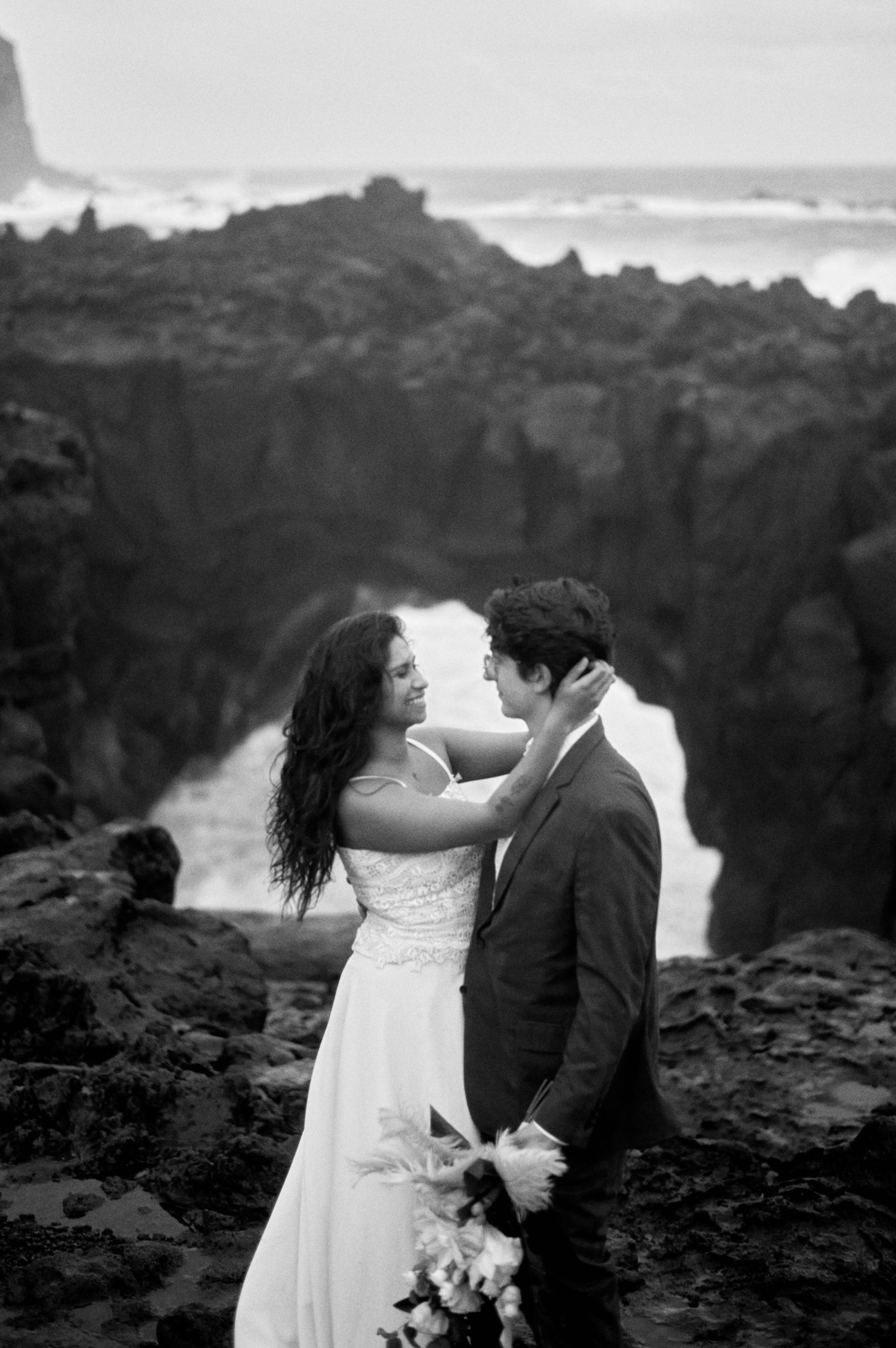Couple embracing in the sea spray at Ponta da Ferraria, black and white, São Miguel