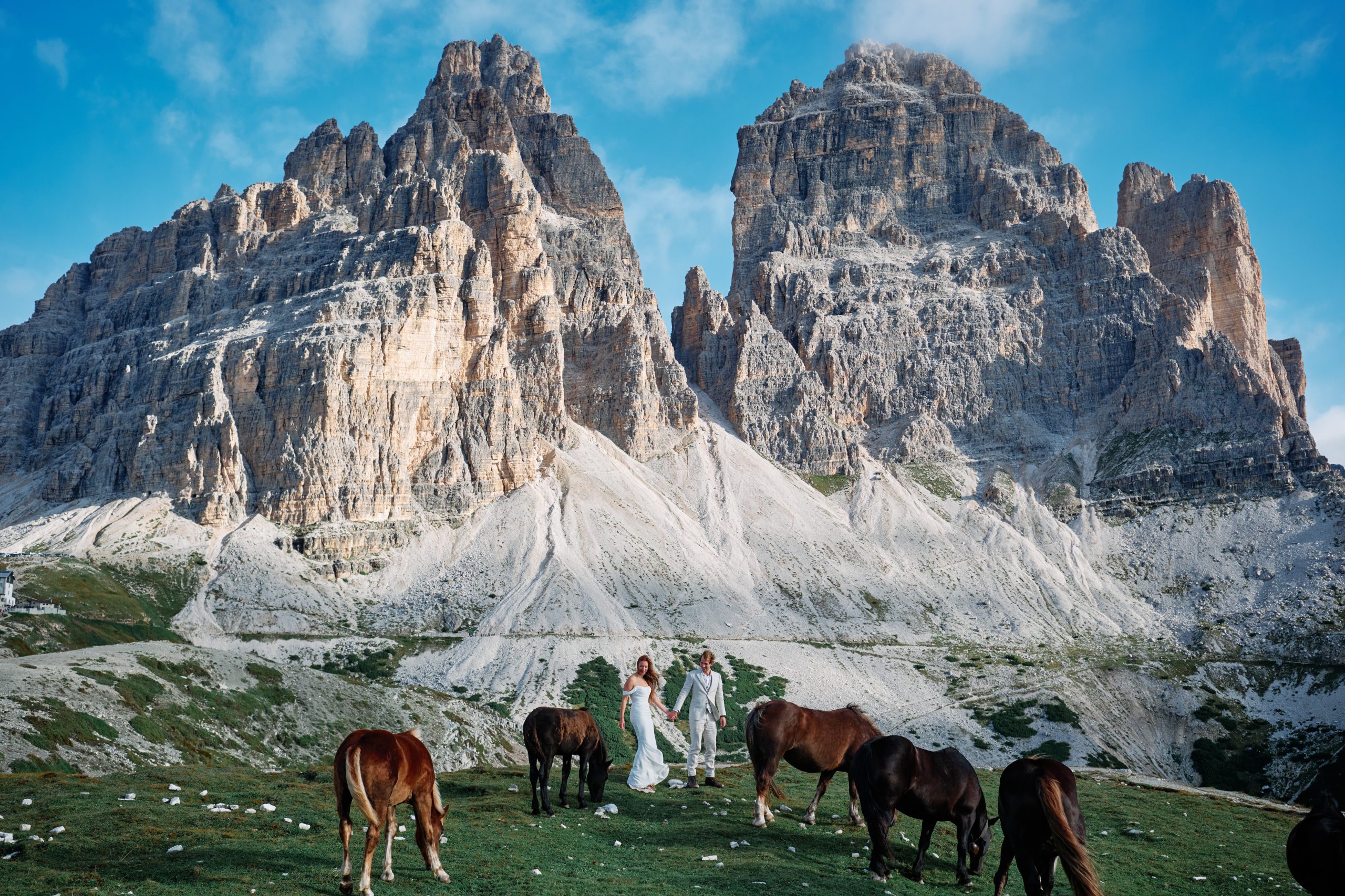 A couple among wild horses beneath Tre Cime in the Dolomites