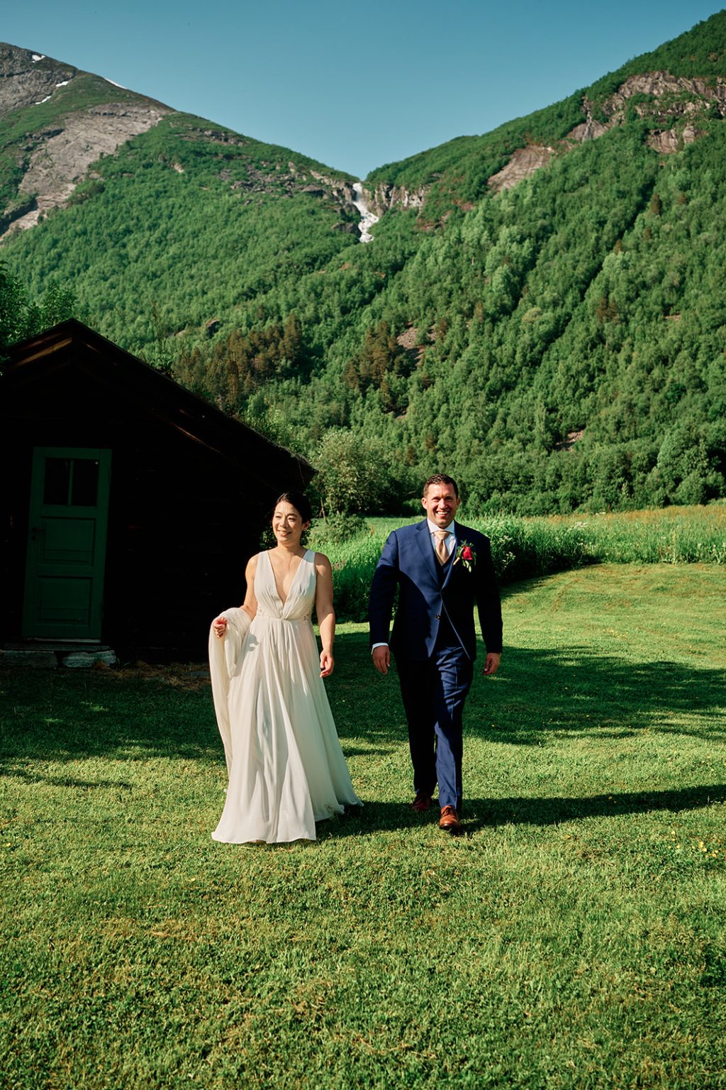 The couple by a turf-roofed cabin below the mountains