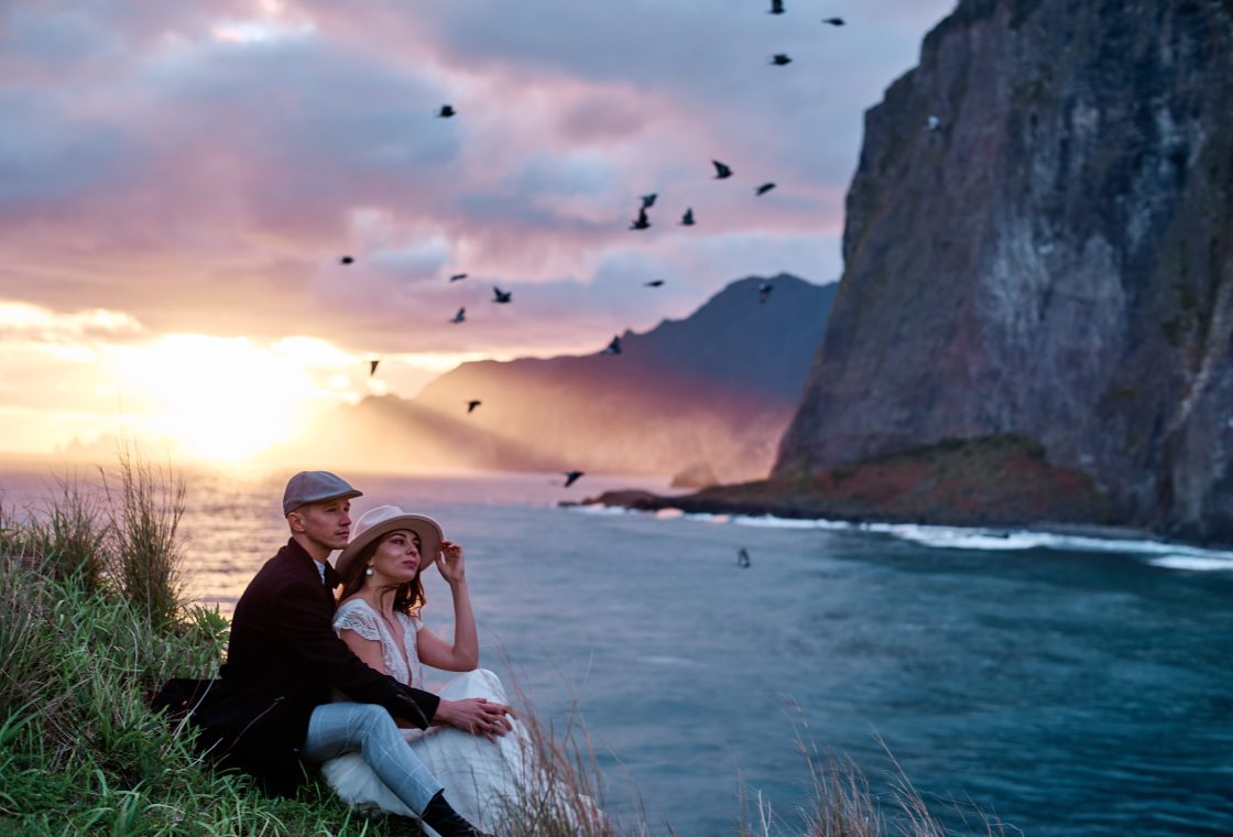 Birds over the sea cliffs at sunrise as a couple embraces, Miradouro do Guindaste, Madeira engagement photographer