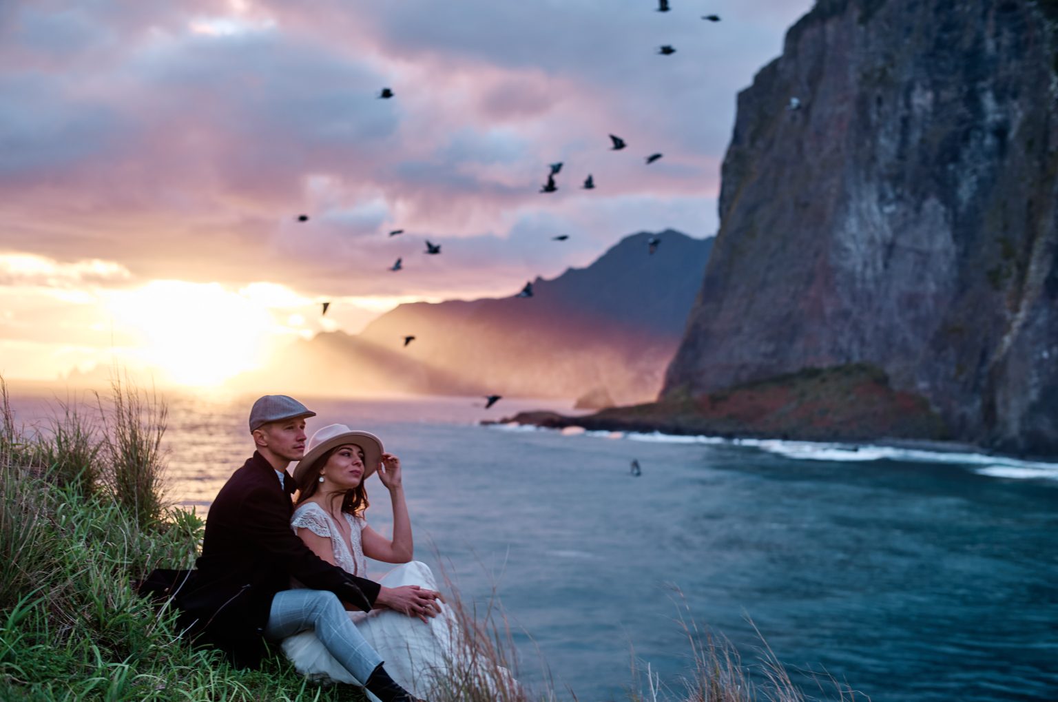 Birds over the sea cliffs at sunrise as a couple embraces, Miradouro do Guindaste, Madeira engagement photographer