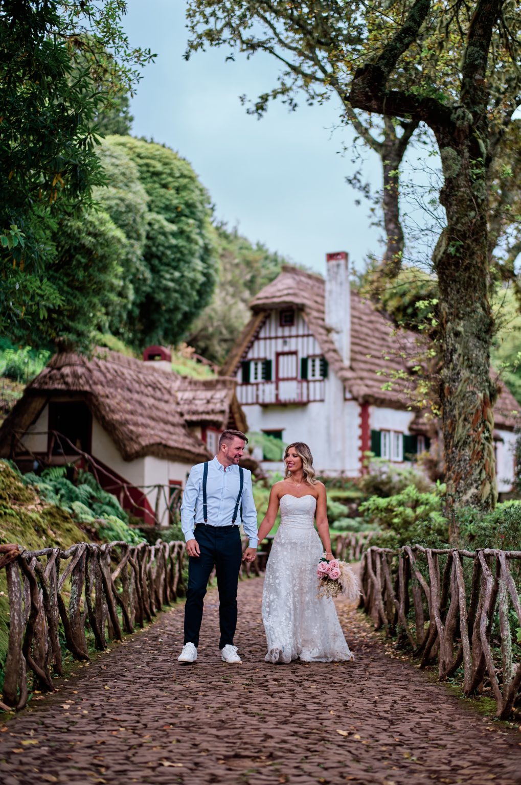 Bride and groom by a red-roofed house in the laurel forest, Madeira
