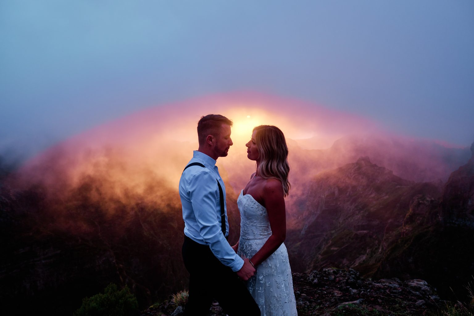 Couple silhouetted against a fiery pink and orange sky at sunset, Pico do Arieiro, Madeira