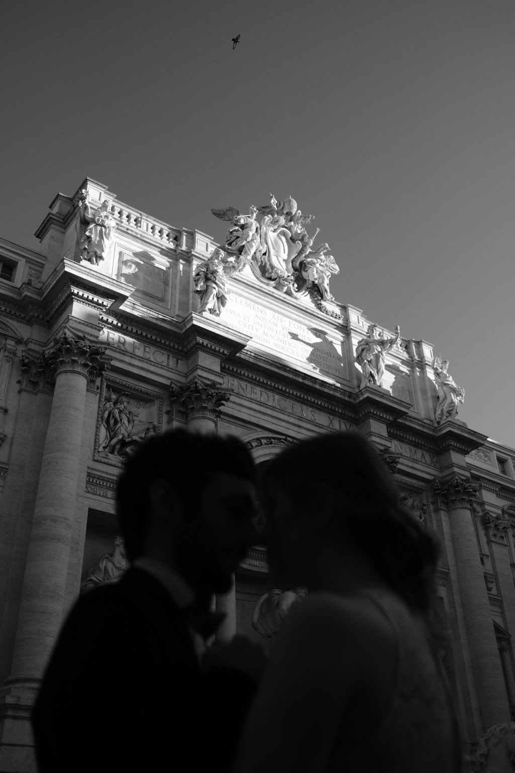 The Trevi Fountain rising above the couple in soft focus