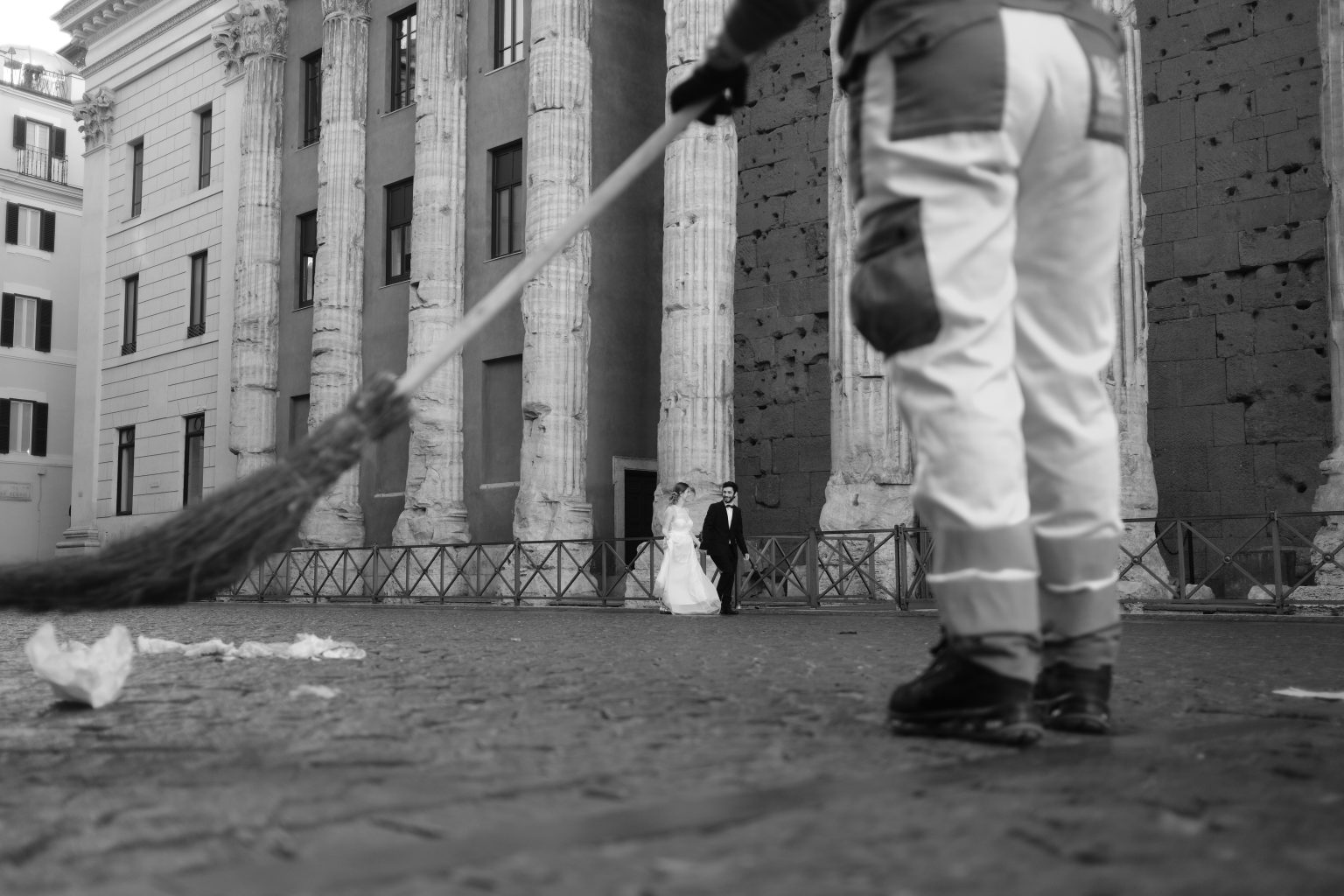 A street sweeper passes the couple in a Roman piazza at dawn