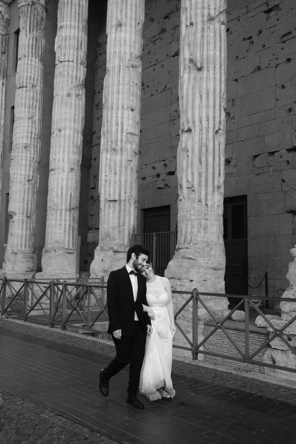 A kiss on the cheek beneath ancient columns in Rome
