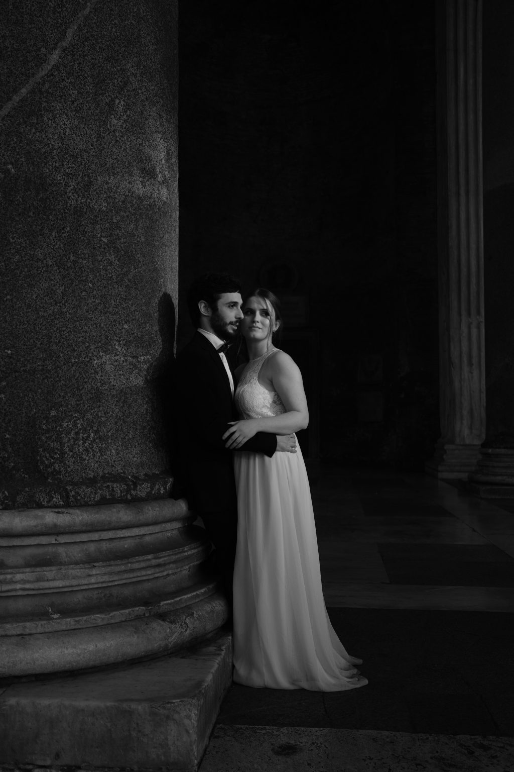 Rozina resting her head on Salvatore’s shoulder against a column