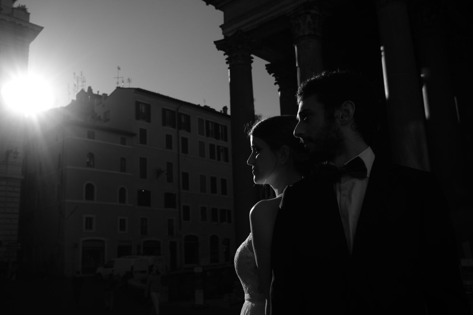 The sun cresting the rooftops of Rome behind the couple