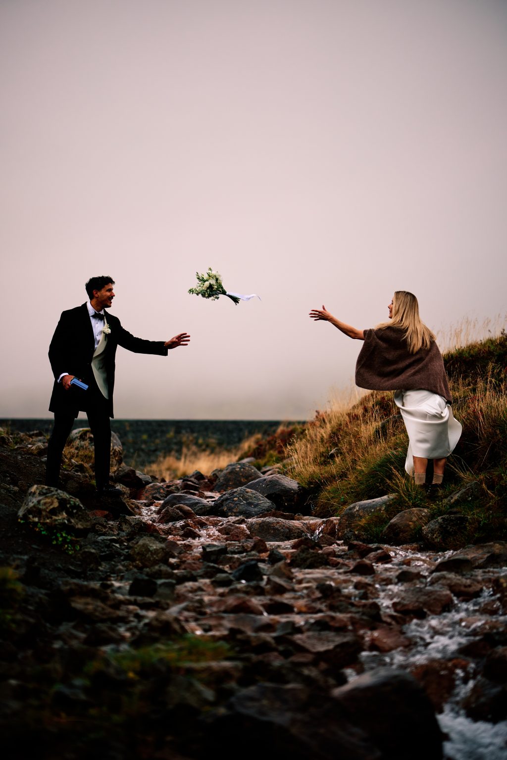 Lindsey tossing the bouquet to Daniel on the walk to their waterfall ceremony