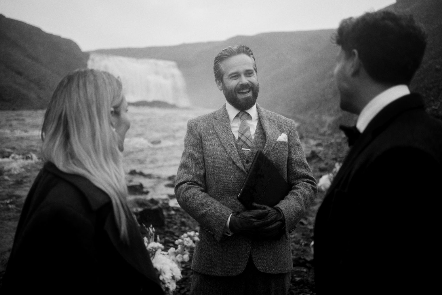 Icelandic celebrant smiling mid-ceremony at Þórufoss