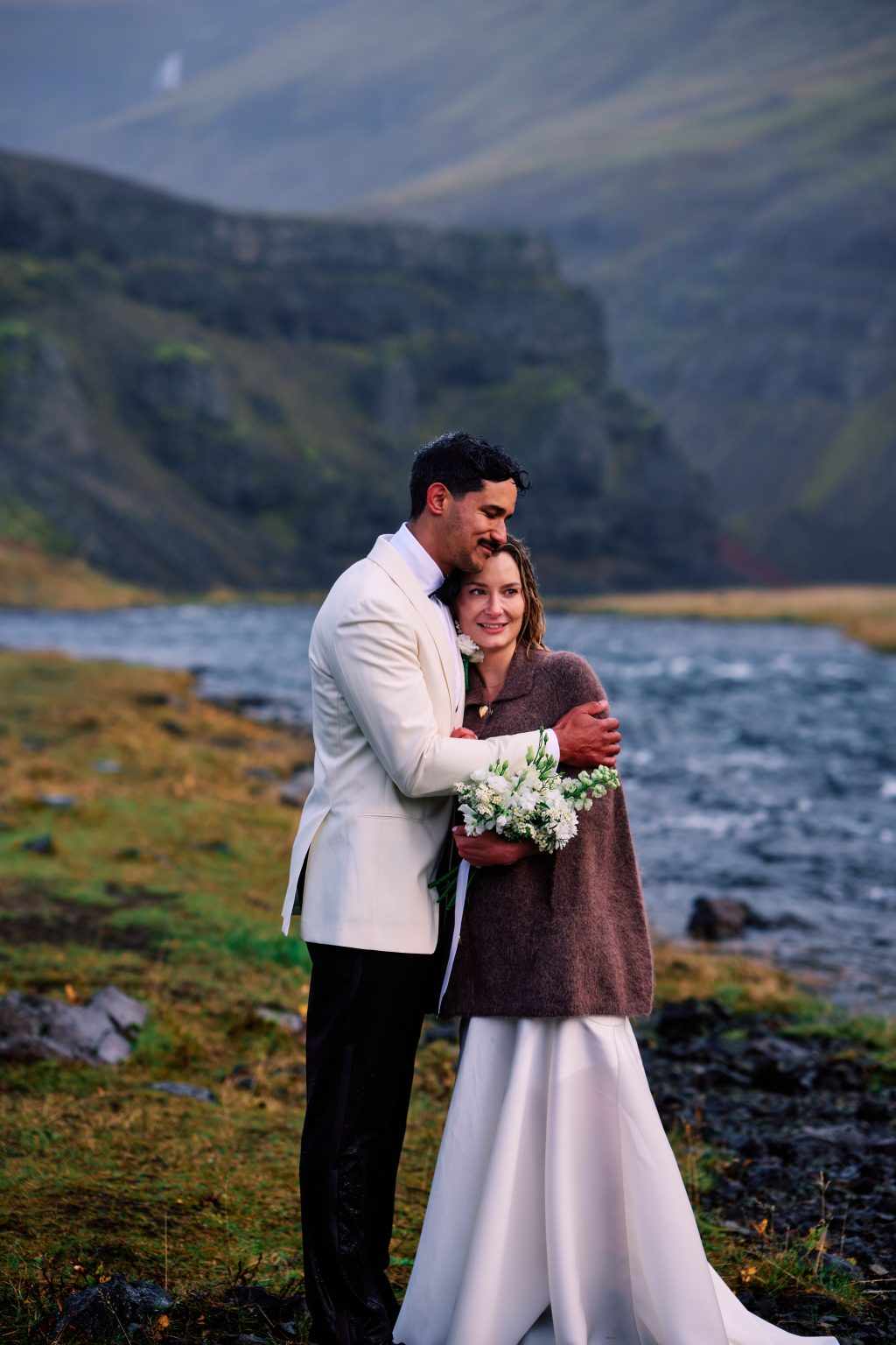 Newlyweds embracing with the bouquet at Þórufoss, Iceland